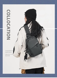 Detail of dark gray nylon crossbody bag on model with adjustable strap and charm