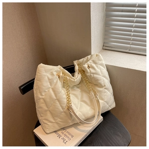 Detailed shot of beige quilted nylon fabric and gold chain strap on a designer tote bag