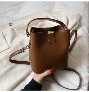 Detail of a brown leather bucket bag with top handle and gold hardware by Macohee