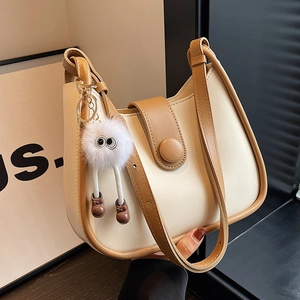 Minimalist beige and brown color-block bucket bag with plush monster charm decoration