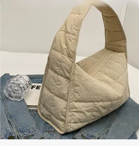 Detailed close-up of cream quilted canvas tote with diamond stitching and zipper