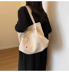 Detail of colorful embroidered letters and leather logo tag on a canvas tote bag