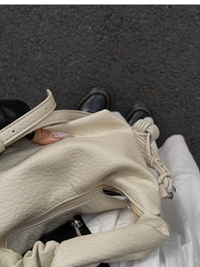 Détail d'un sac en cuir plissé blanc crème montrant la texture et la poignée nouée