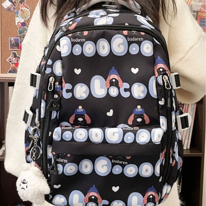 Grand sac à dos noir avec imprimés cartoon et breloque en peluche en décor intérieur