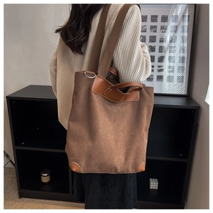 Detalle de bolso tote de lona con adornos de cuero marrón y correa ancha para el hombro