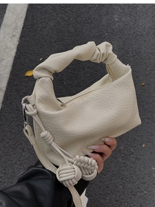 Détail d'un sac à main plissé blanc cassé avec boules tressées et cuir grainé