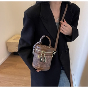 Détail d'un sac seau cylindrique marron vintage avec foulard élégant sur la poignée
