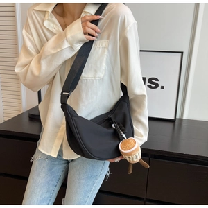 Detail of black nylon crescent crossbody bag featuring a cute coffee cup plush charm