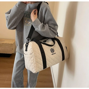Detail der cremefarbenen Stepp-Reisetasche mit großem Fassungsvermögen und Schultergurt