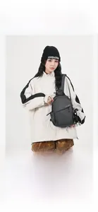 Detail of dark gray nylon crossbody bag with black monkey plush keychain on strap