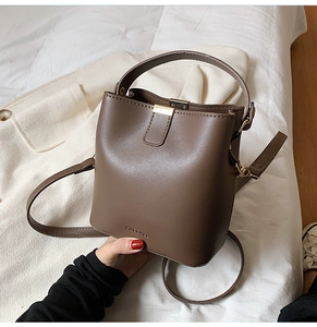 Top-down view of a matte dark brown leather bucket bag with top handle and hardware detail