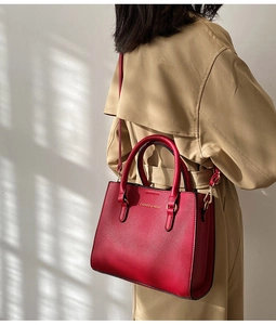 Detailed back view of a red pebble leather handbag with gold logo and adjustable strap
