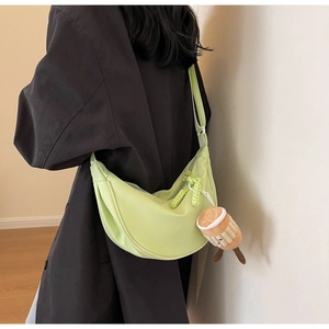 Detail of light green nylon crescent bag with woven zipper pull and plush cup charm