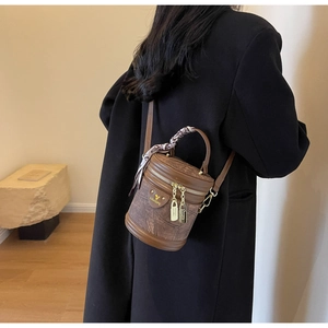 Détail d'un sac seau vintage en cuir texturé marron avec foulard décoratif en soie