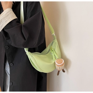 Close-up of mint green crescent nylon bag with adjustable wide strap and plush charm