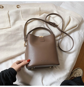 Detail view of coffee brown leather bucket bag with gold hardware and brand logo