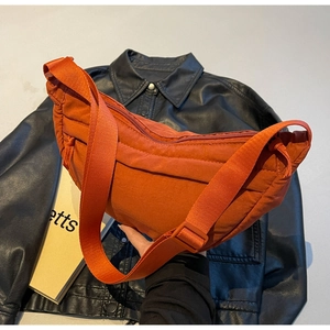 Close-up of burnt orange puffy nylon tote bag with quilted stitching and wide strap