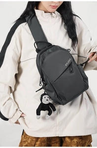 Detail view of water-resistant nylon crossbody bag with zipper and monkey keychain charm