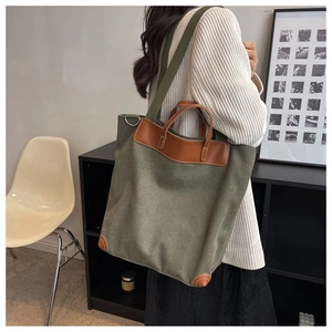 Detalle de bolso tote de lona verde militar con asas de cuero y correa de tela al hombro