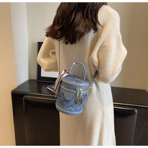 Sac seau en denim bleu avec foulard en soie décoratif porté à l'épaule par un mannequin