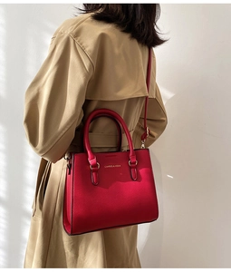 Detail of red textured leather bridal handbag with gold metal hardware and top handle