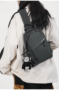 Detail of black crossbody chest bag with plush monkey charm and stlangs logo print