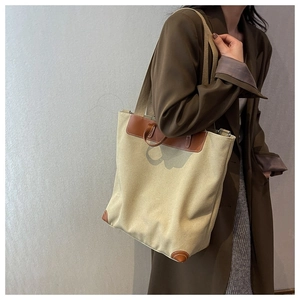Primer plano de un bolso tote de lona grande con asas y esquinas de cuero marrón