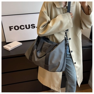 Close-up of grey waterproof travel bag with adjustable strap worn by a model in modern setting
