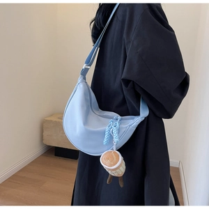 Detail of light blue hobo bag with wide strap and cute coffee cup plush charm
