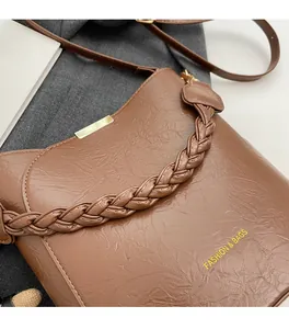 Detail of brown pleated PU leather bucket bag with woven handle and gold hardware