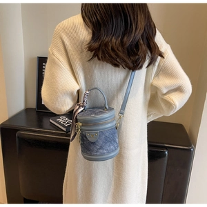 Détail d'un sac seau en denim bleu clair avec garniture dorée et foulard en soie