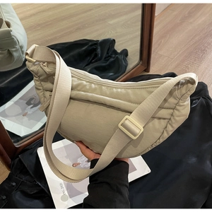 Detailed close-up of beige quilted nylon crescent bag with adjustable wide shoulder strap
