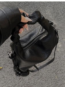 Vue détaillée du sac à main plissé noir avec texture craquelée et détail de nœud
