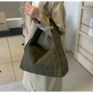 Quilted olive green canvas tote bag with rhombic stitching shown in a minimalist setting