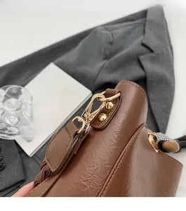 Detail of brown vintage bucket bag with polished gold hardware and checkered scarf decoration