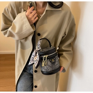 Détail du sac seau en denim gris avec garniture en cuir noir et foulard en soie décoratif
