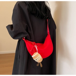 Red nylon crescent bag with plush coffee cup charm shown on black trench coat