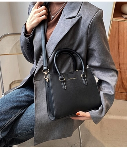 Detail of black lychee grain leather handbag with gold CAIRES & HEXA logo and hardware