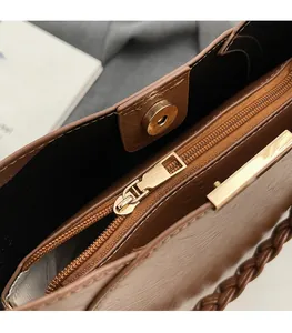 Detail view of brown leather bucket bag featuring gold zipper and magnetic buckle closure