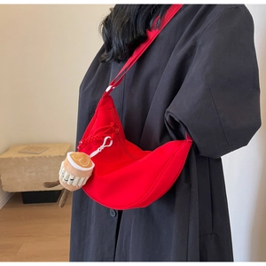 Red nylon crescent bag with plush coffee cup charm on wide shoulder strap