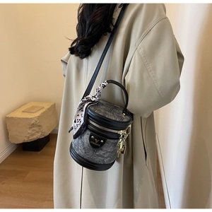 Détail du sac seau gris avec bordure en cuir et foulard en soie décoratif