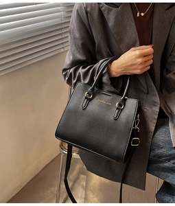 Detail of black lychee grain handbag with gold hardware and logo on leather surface