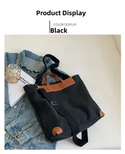 Detail view of large black canvas tote bag with brown leather accents and long strap