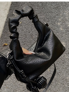 Détail d'un sac à main noir plissé avec texture litchi et boules tressées