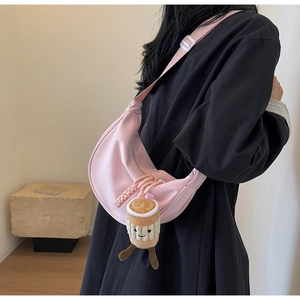 Pink nylon crescent bag detail featuring a cute plush coffee cup charm and wide strap