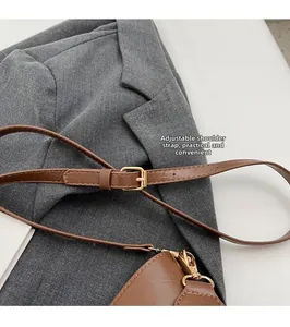 Detail of adjustable brown leather shoulder strap with gold hardware on a bucket bag
