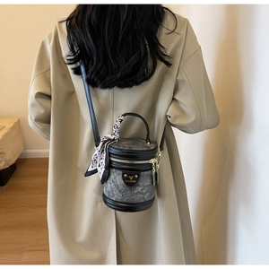 Détail d'un sac seau cylindrique vintage avec texture gaufrée et foulard en soie élégant