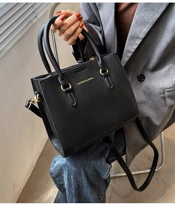 Chic black litchi pattern leather handbag with gold logo shown in a street style scene