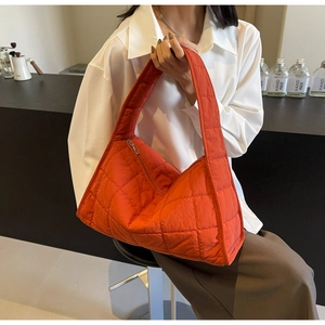 Detail of bright orange quilted tote bag with soft diamond texture and large capacity