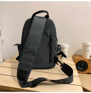 Detail of high-capacity dark gray crossbody bag with adjustable wide strap on a wooden bench